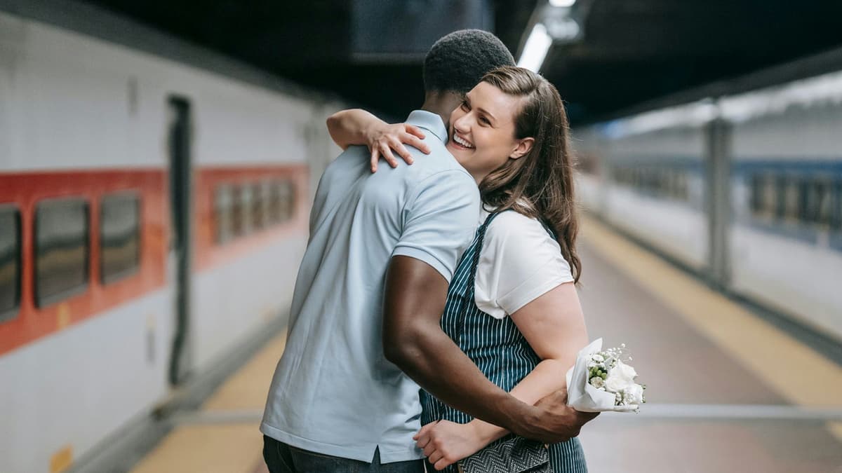 A joyful couple hugging on a train platform capturing the essence of love and togetherness.