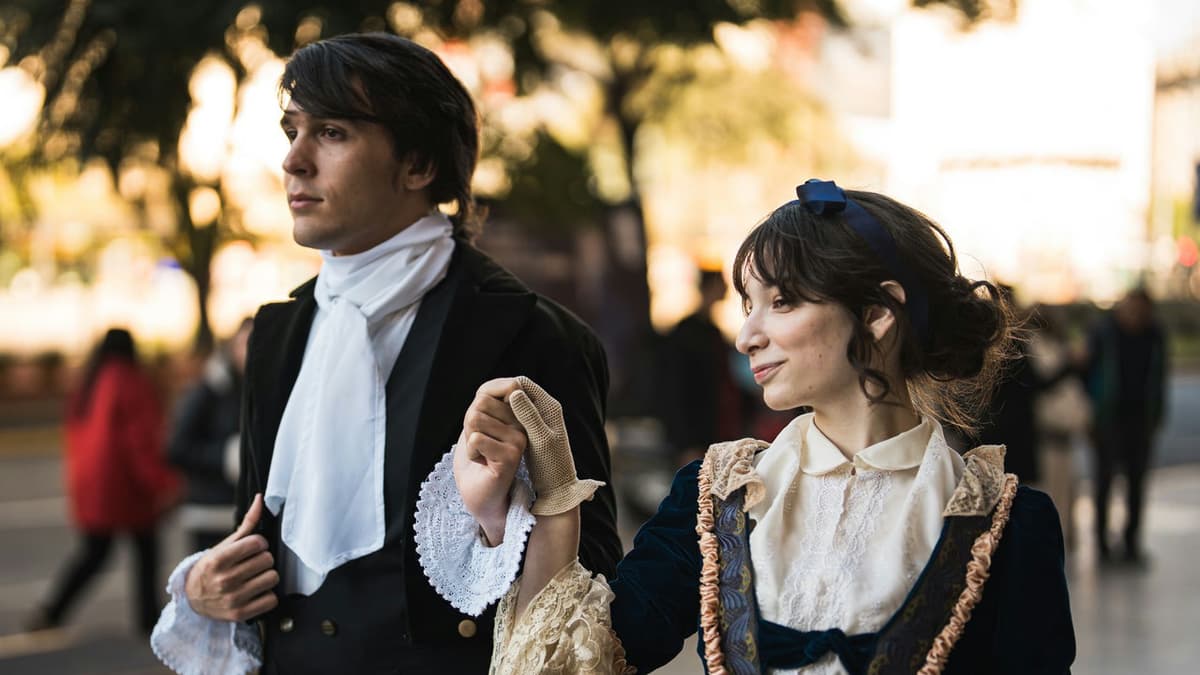 A couple dressed in vintage outfits walking outside in urban setting.