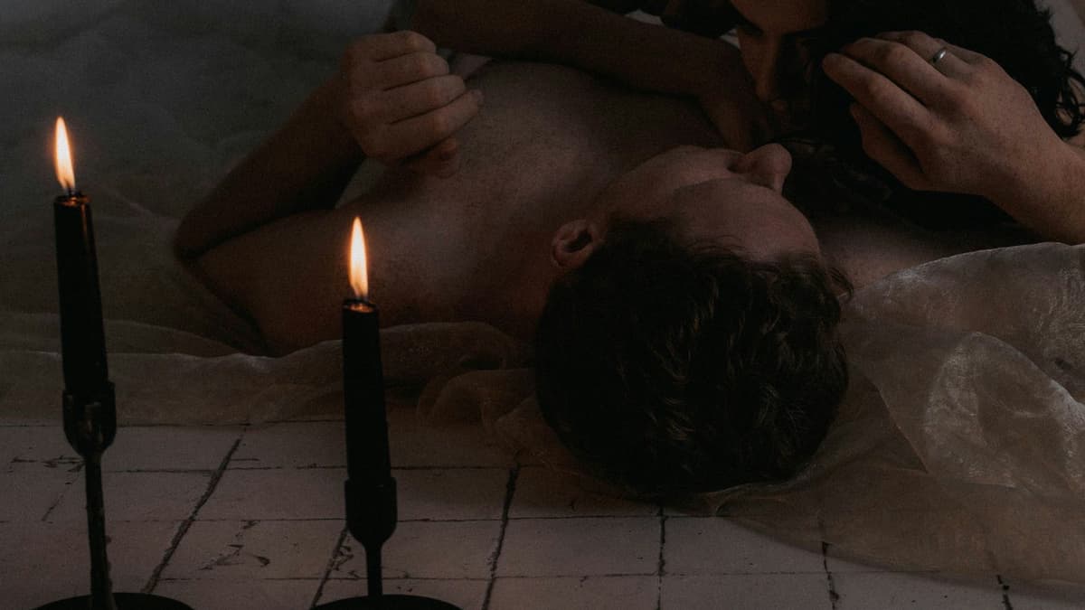 Romantic scene of a loving couple embracing by candlelight, creating a warm, intimate atmosphere.